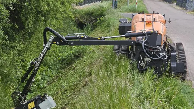 Funkraupe mit Auslegearm mäht einen Grabenrand frei